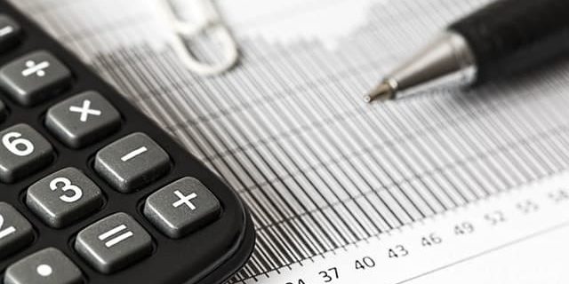 Kalkulator i długopis na wydrukach finansowych