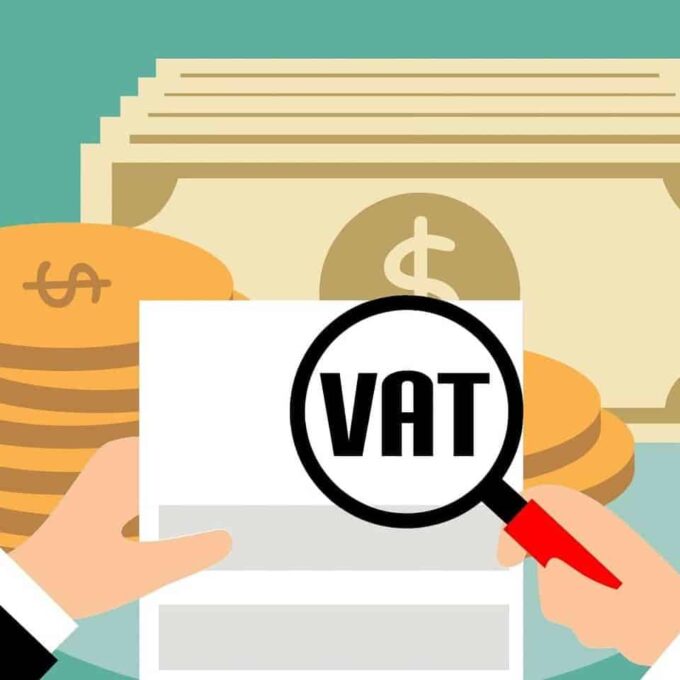 Dłonie z lupą nad fakturą z napisem VAT i monetami