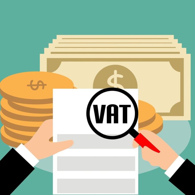 Dłonie z lupą nad fakturą z napisem VAT i monetami