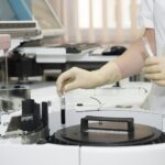 Laborant w rękawiczkach przy urządzeniu laboratoryjnym