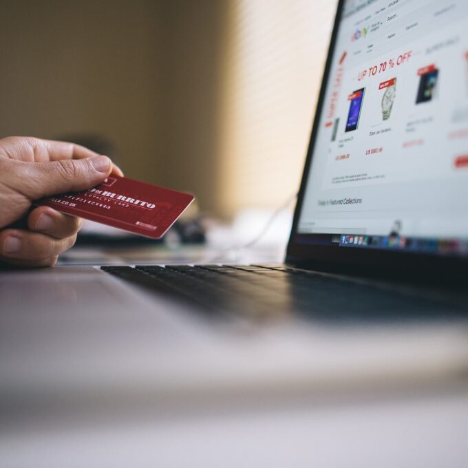 Dłoń z kartą płatniczą przy laptopie ze sklepem internetowym